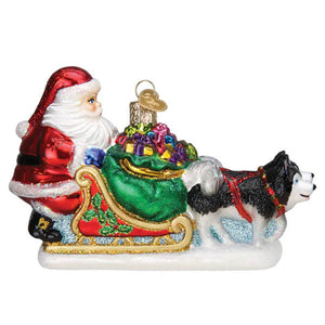 Red and white santa claus in a glass dog sled ornament pulled by a black and white husky filled with colorful gifts