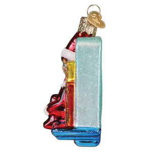 A festive glass christmas ornament featuring santa in red and white with a glittery blue book for scout elf storytime