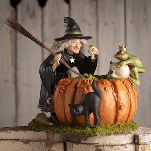 A detailed figurine of a smiling halloween witch in black robe holding prince potion cup with pumpkin and black cat