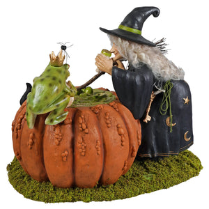 A whimsical halloween witches figurine in black cloak with gold stars blowing a pipe beside a prince potion pumpkin