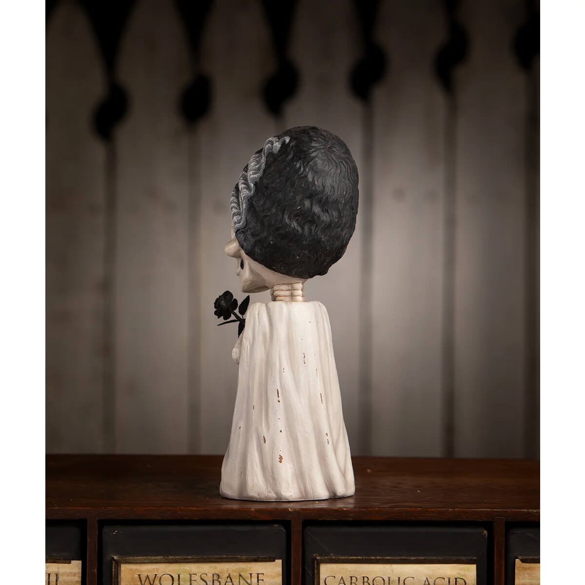 A white textured skeleton figurine with black hair in a wedding dress holding a black rose shelley skelly