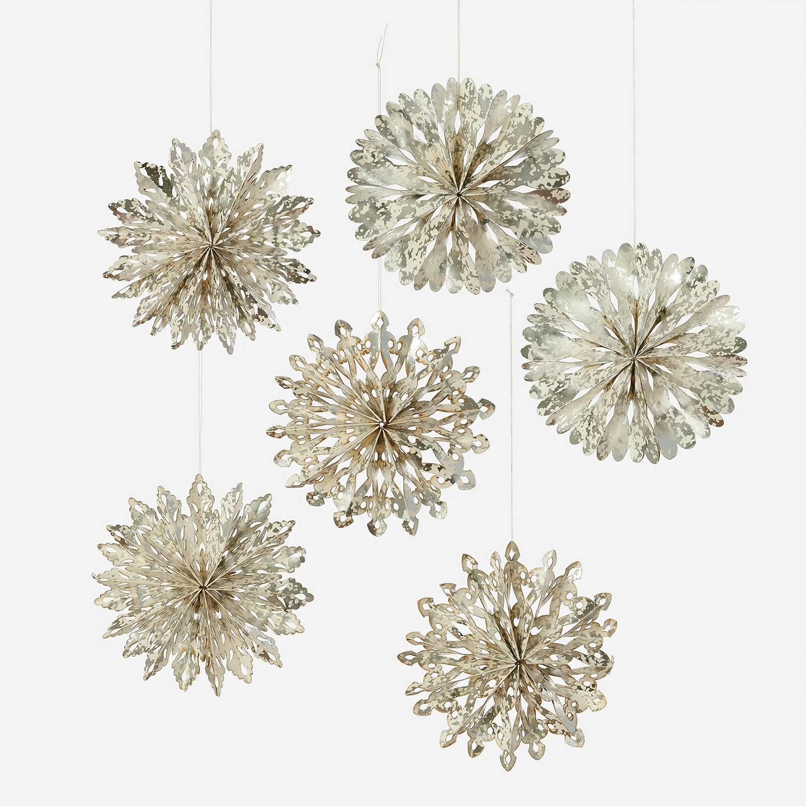 Silver cutout snowflake ornaments made of metallic paper hanging from strings in a snowflake ornaments boxed set 6