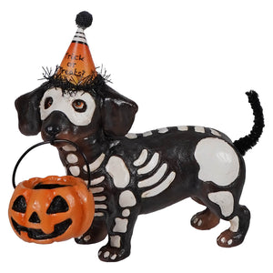 Skeleton pup table piece dachshund skeleton figurine wearing a halloween hat holding an orange pumpkin bucket
