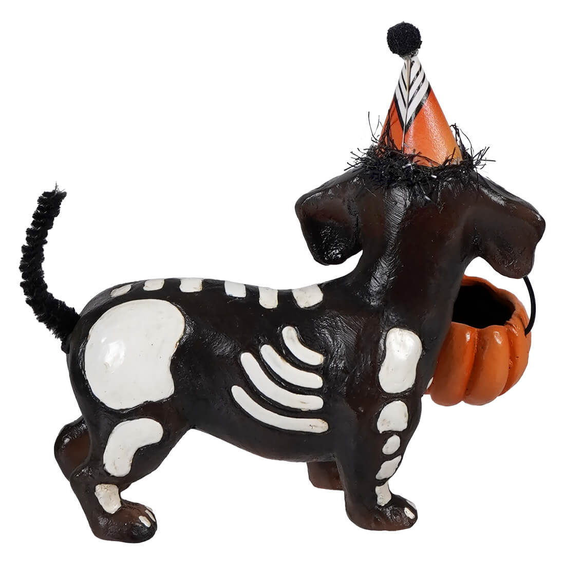 A black and white skeleton pup table figurine wearing an orange party hat holding a pumpkin basket for decoration