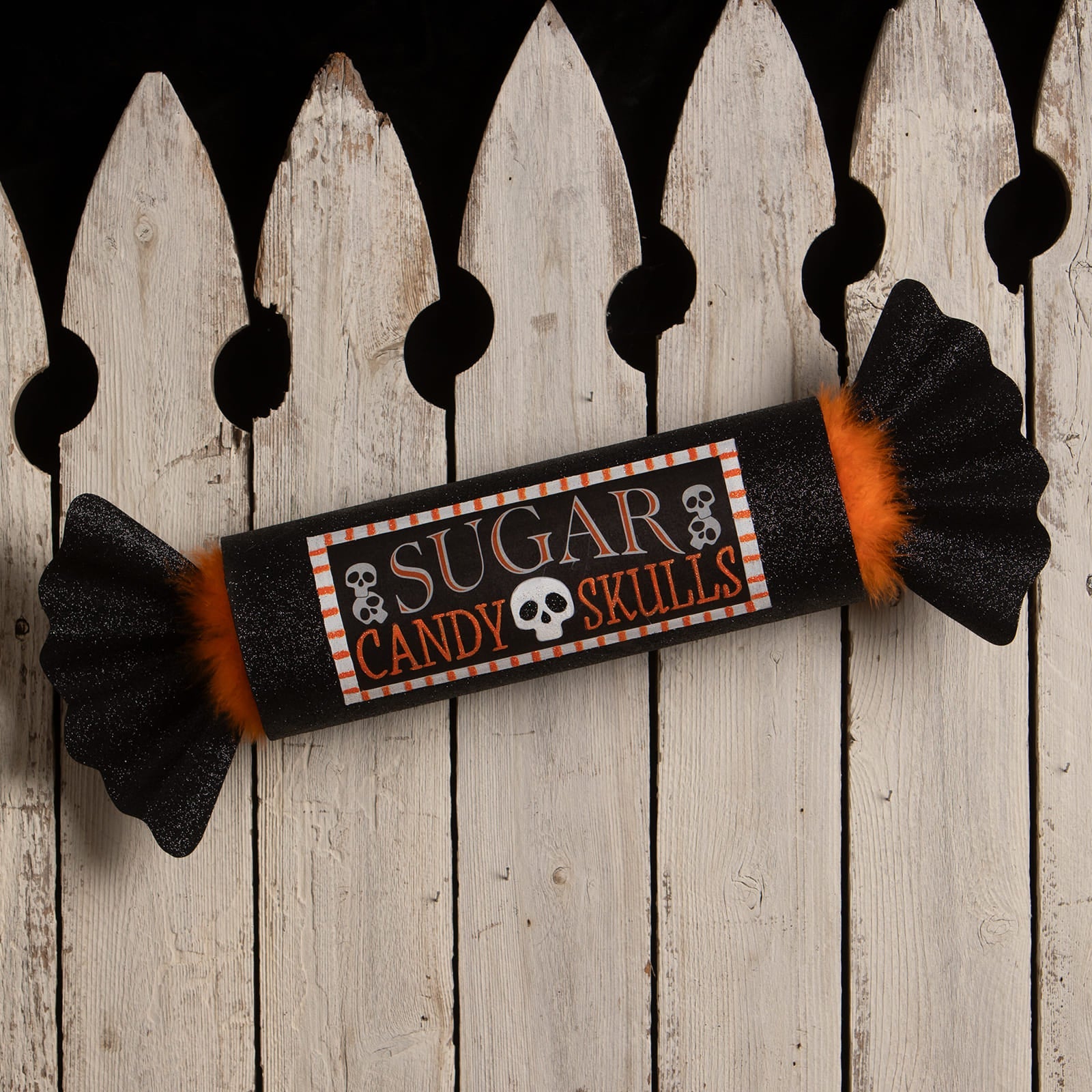 Black glittery candy wrapper with orange fuzzy ends labeled sugar candy skulls featuring skull icons for bethany lowe halloween candy