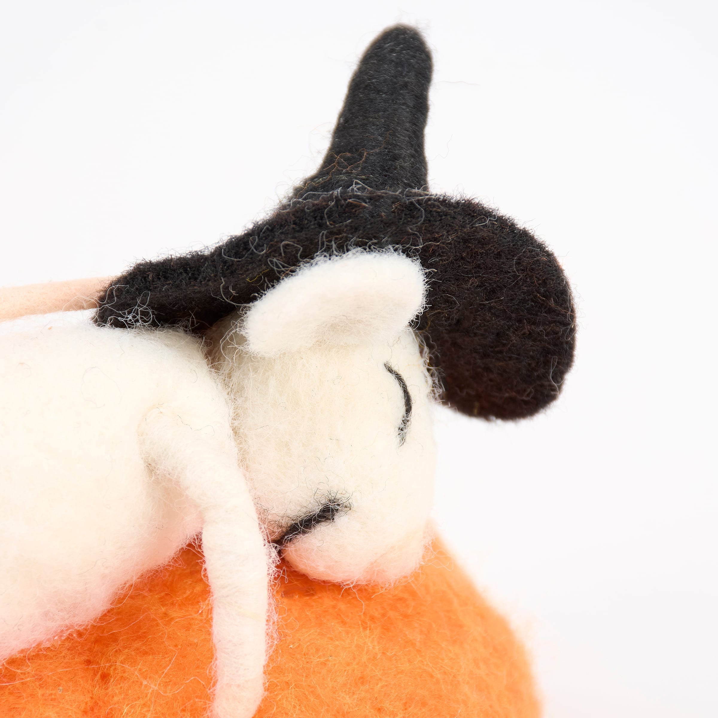 A white felt sleepy witch mouse critter wearing a black witch hat from kathy’s halloween collection resting on orange