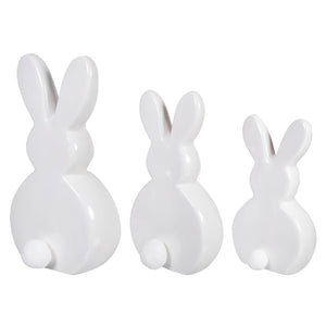 Three white ceramic bunny figurines lined up in a row.