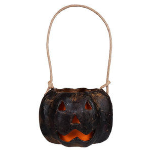 Small carved black pumpkin bucket made of hand-painted paper mache with glowing orange interior and natural twine handle