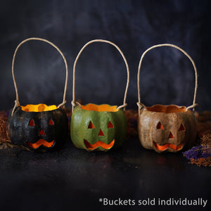 Three small carved black pumpkin buckets with spooky faces made from hand-painted paper mache and woven handles