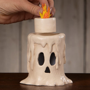 Cream-colored ceramic skull-shaped candle luminary with a faux flame on top for small flam’in candle luminary