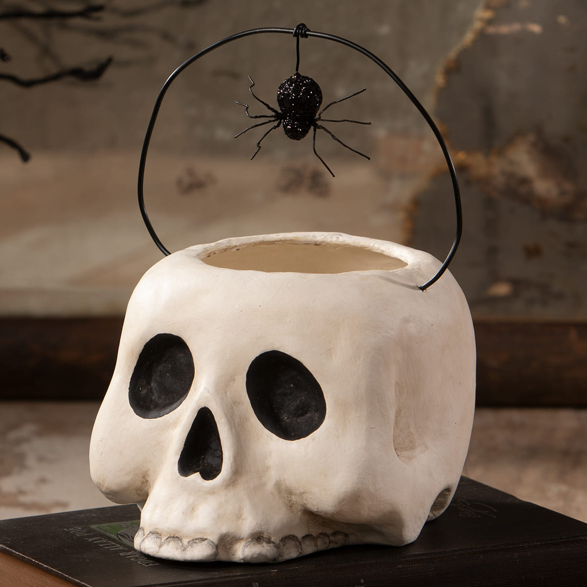 Small grim bucket is a white ceramic skull candy bucket with black eye sockets and a spider ornament halloween buckets and lanterns