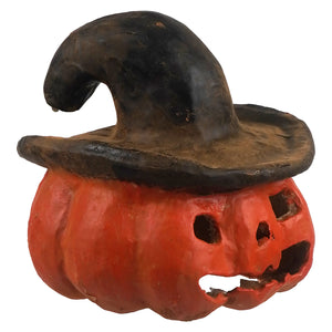 A small rustic orange pumpkin jack o lantern figurine wearing a weathered black witch’s hat with a brown brim