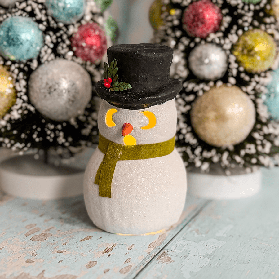 White glittery snowman luminary surprised with black top hat holly yellow crescent eyes orange nose green scarf by bethany lowe designs