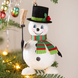 A cheerful white bethany lowe design snowman ornament with black top hat striped scarf holding broomstick