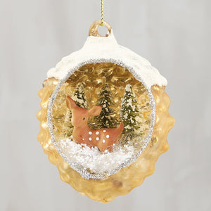 A golden snowy deer glass ornament with textured finish and miniature deer in faux snow for year-round decor