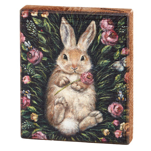 Adorable brown bunny rabbit sitting among pink roses.