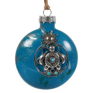A vibrant blue glass southwestern turtle christmas ornament with silver turtle design and turquoise cactus accents