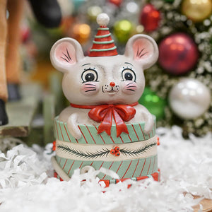A charming white ceramic mouse figurine with red green party hat and red bow on a mint green striped gift box by bethany lowe designs