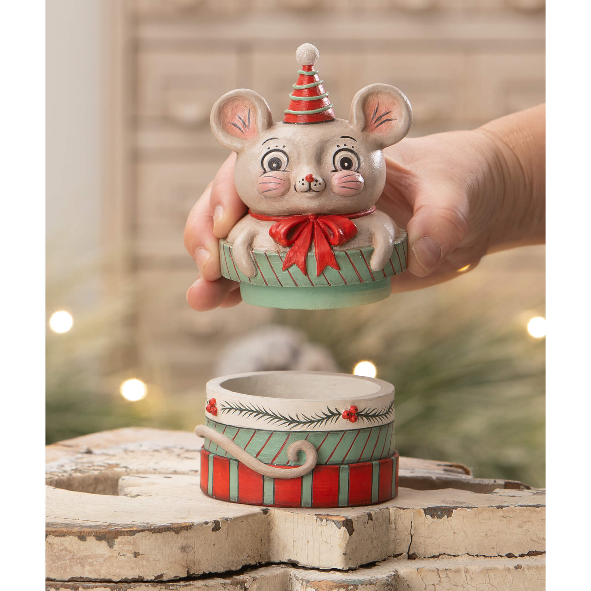 A cream ceramic mouse figurine with a red striped party hat and bow on a festive gift box from bethany lowe designs