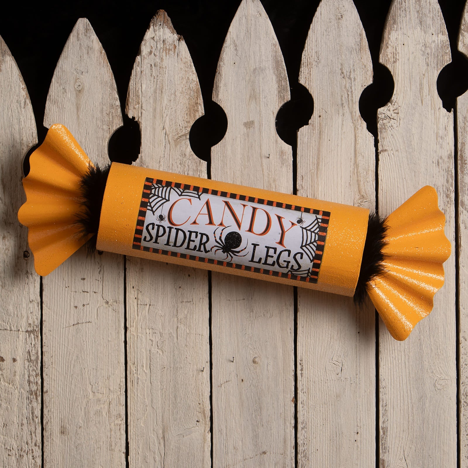 Spicy legs candy by bethany lowe is a bright orange candy-shaped decor with black fuzzy ends and candy spider legs label