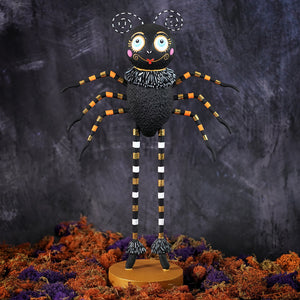 Spinderella halloween figure with black body, oversized eyes, orange gold striped legs, and frilly collar on gold base for halloween display
