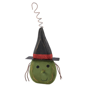 A rustic green wooden witch figurine with a black hat and red glitter band from a vintage inspired spooky ornament set