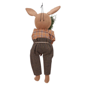 Tan fabric spring rabbit doll dressed in plaid shirt and dark checkered pants holding greenery spring rabbit ornament