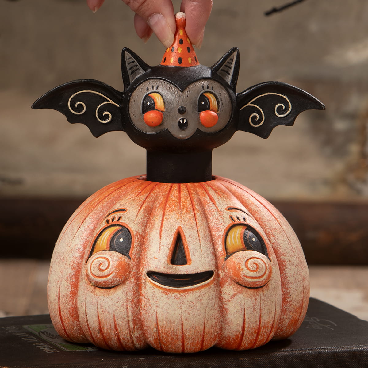 A whimsical ceramic squatty pumpkin batty figurine with a smiling orange pumpkin and black bat for halloween pumpkins and gourds
