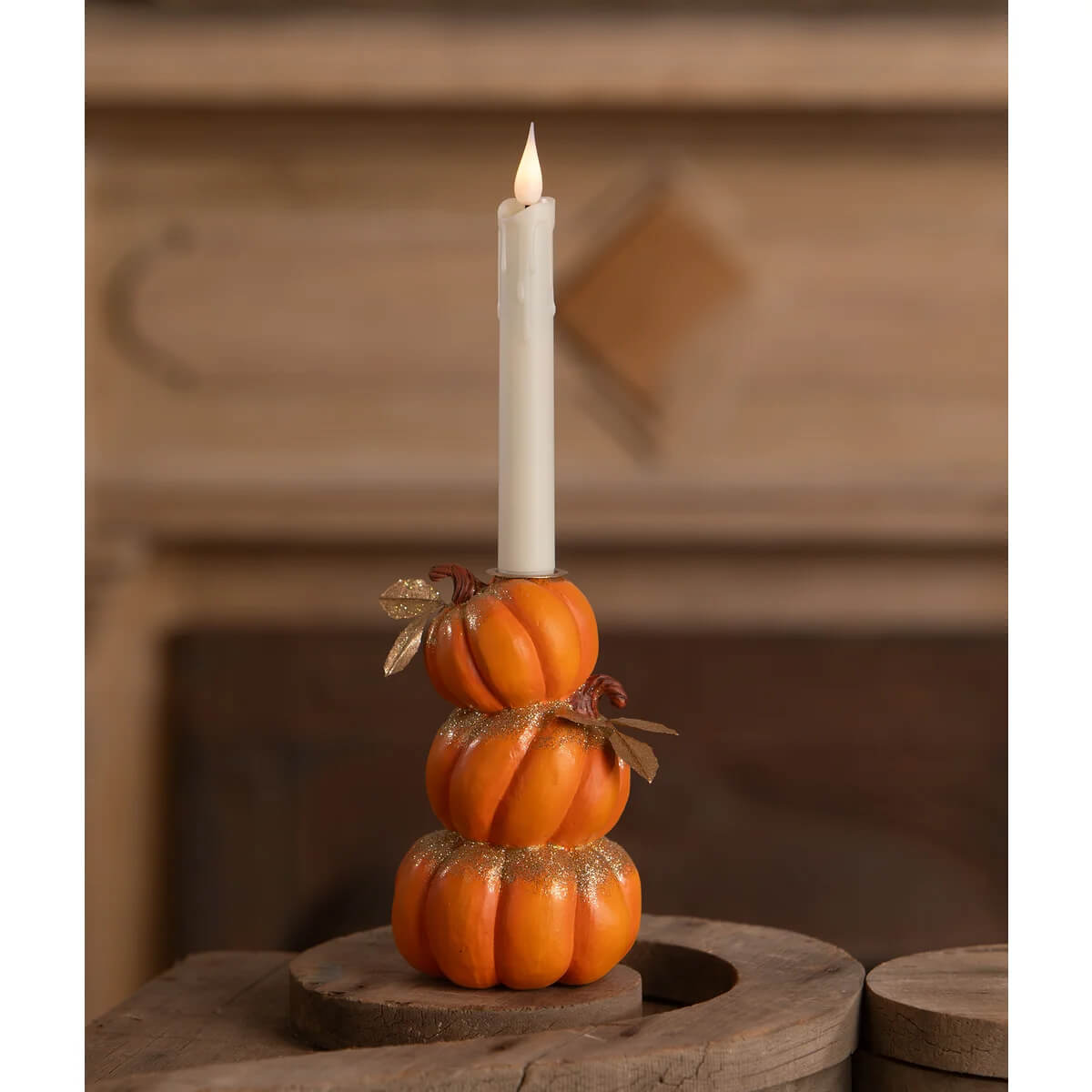 Orange hand-painted resin stack of pumpkins candle holder with glittery accents and a white electric candle by bethany lowe