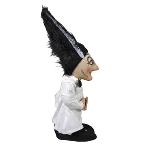 A whimsical standing carmella stein doll wearing a tall black feathered hat with white lace trim and white blouse