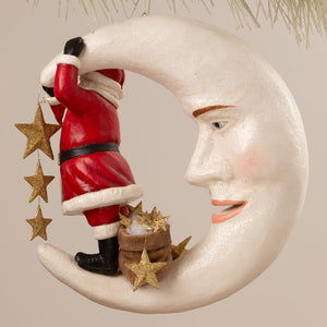 A whimsical white glittery crescent moon ornament with a smiling face featuring santa claus from bethany lowe designs folk art santas