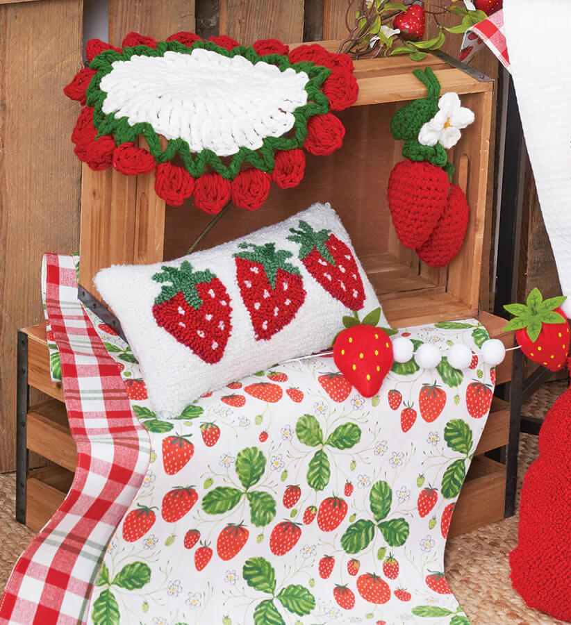 Decorative pillows with strawberry patterns and crochet details.