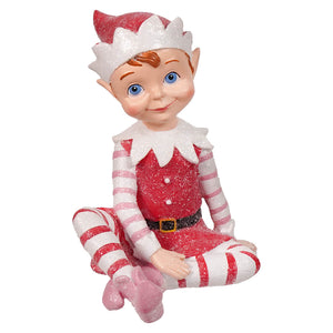 A glittery red and white resin elf figurine with blue eyes wearing a striped outfit and pink shoes sugar coated sweet