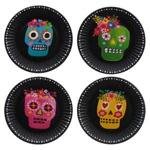 Four colorful sugar skulls decorated with floral patterns on black circular plates.