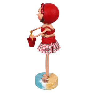 Red lori mitchell summer figurine of a girl in red top and checkered skirt holding a bucket on a painted beach base