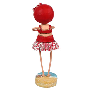 Red spherical-headed lori mitchell figurine wearing a red bikini top and checkered skirt on a summer beach base