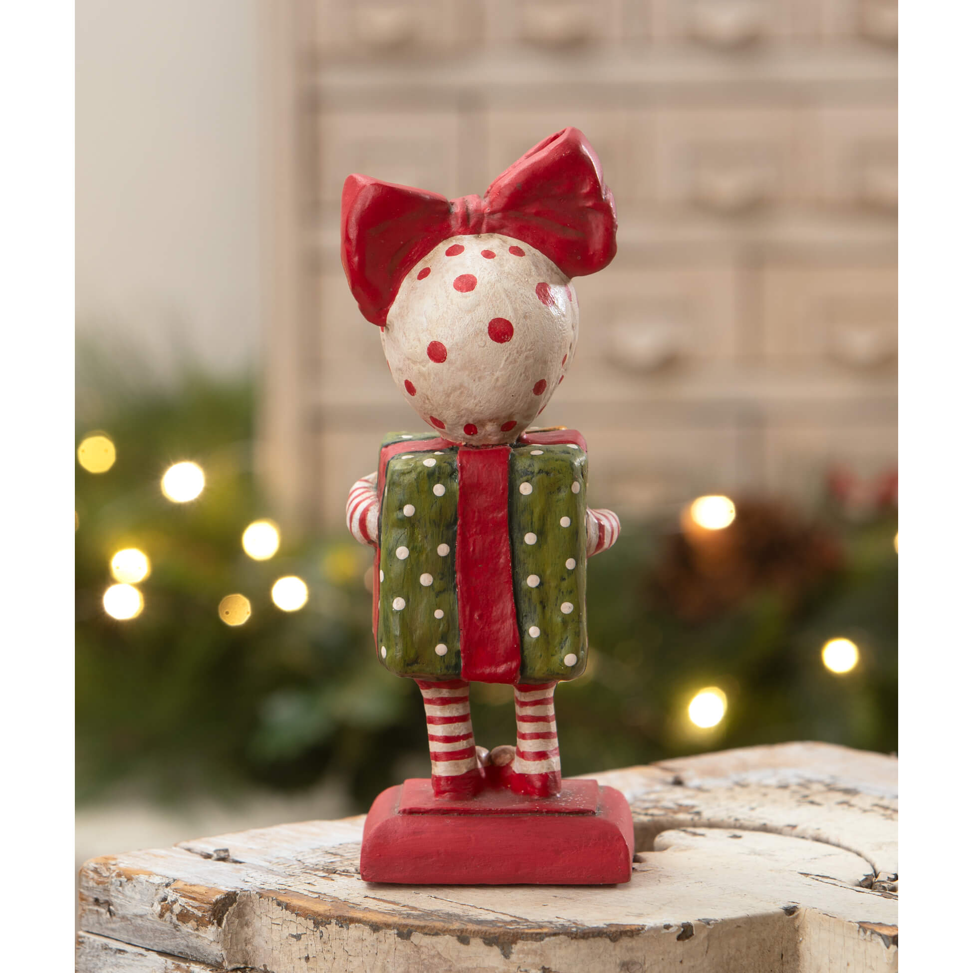 A whimsical surprise package girl figurine by bethany lowe designs holding a green gift spreading holiday cheer