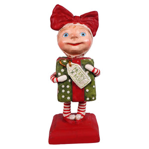A cheerful surprise package girl figurine by bethany lowe designs with blue eyes holding a green polka-dotted gift spreading holiday cheer