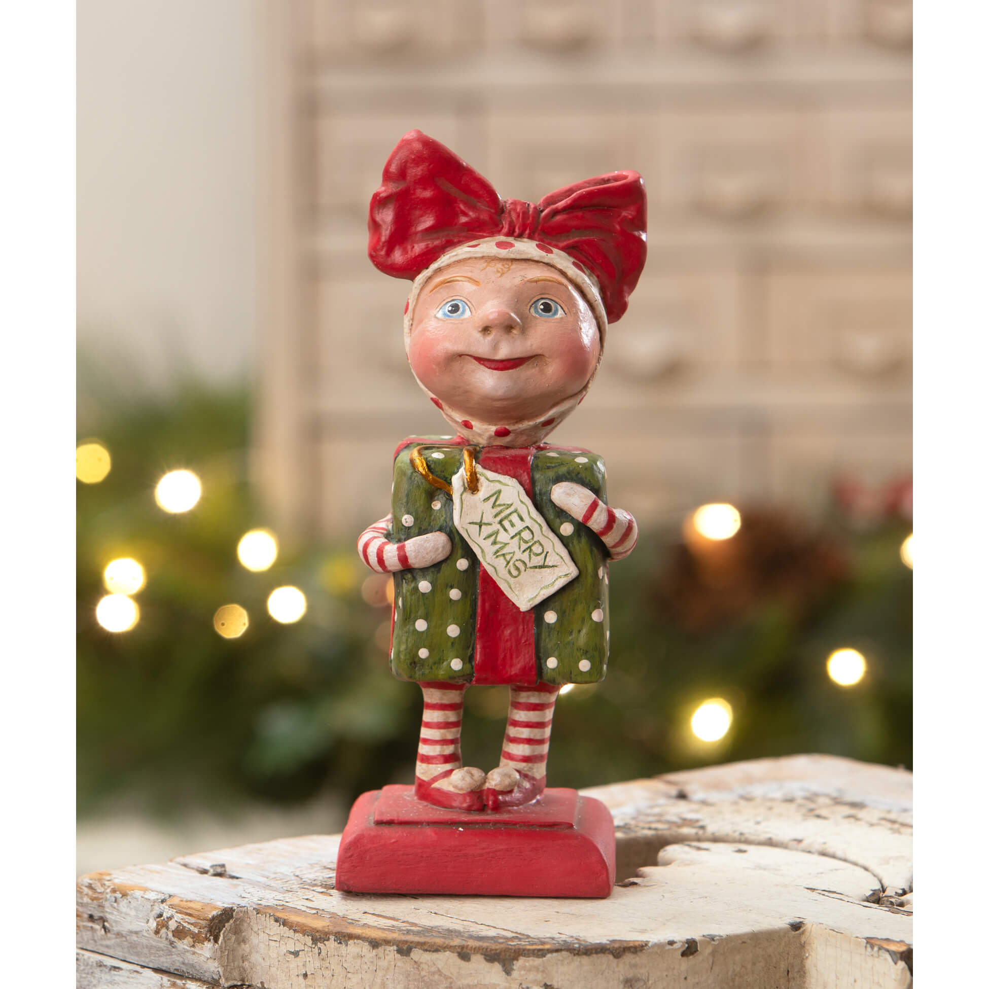 A cheerful bethany lowe designs surprise package girl figurine in red and green polka-dot clothes spreading holiday cheer