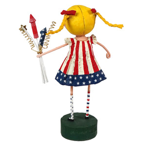 Yellow-haired lori mitchell susie sparkle figurine with red bow pigtails and patriotic striped dress on green base