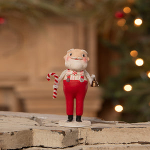 A charming sweet santa figurine in red overalls and striped shirt holding a candy cane from bethany lowe designs