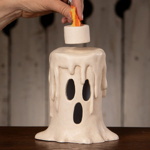 A cream ceramic ghost candle luminary with black eyes and orange flame decor from bethany lowe halloween lanterns