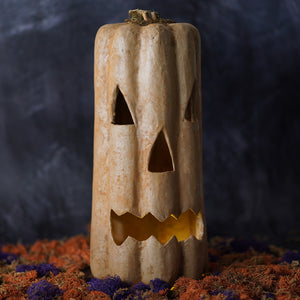 A rustic beige ceramic tall mustard pumpkin jack o lantern with carved face to illuminate pumpkin with battery operated tea light