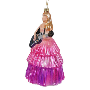A glittering pink and purple glass ornament by cody foster features taylor swift playing guitar in an extravagant dress