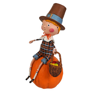 A whimsical lori mitchell thankful thad figurine with orange hair on a pumpkin holding a colorful fruit basket for thanksgiving decor