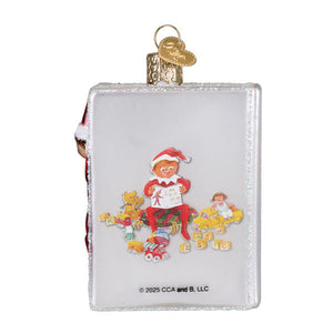 Clear glass book-shaped world christmas shelf ornament with glittery edges and red elf holding a sign surrounded by toys
