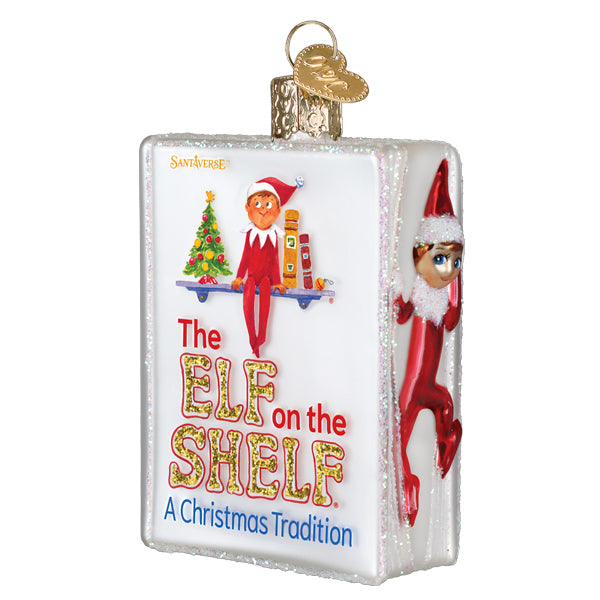 A clear glass world christmas shelf ornament shaped like a book with red elf on the shelf gnomes and elf ornaments