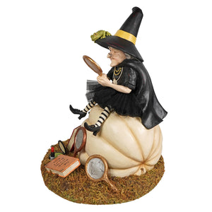 A whimsical figure of the fairest witch seated on a cream pumpkin holding a mirror from bethany lowe designs figural decor