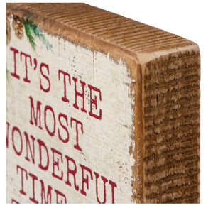 Wooden block with festive text about ’the most wonderful time’ printed on its side.