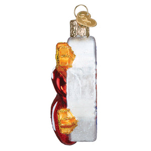 A clear glass rolling stones guitar ornament shaped like a bottle with red gold ribbon and ornate golden cap